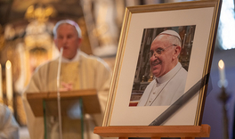 Foto von Franziskus auf einer Staffelei, im Hintergrund Weihbischof Theising